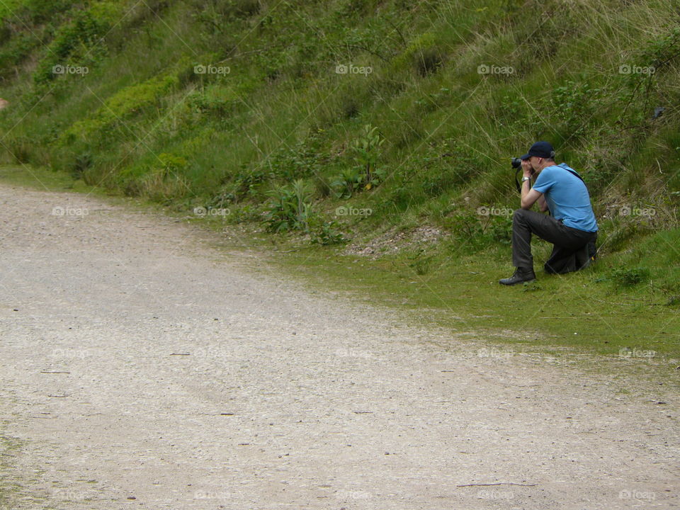 Photographer In Blue Tshirt and cap taking photos on the grass nature photos photography bird watching