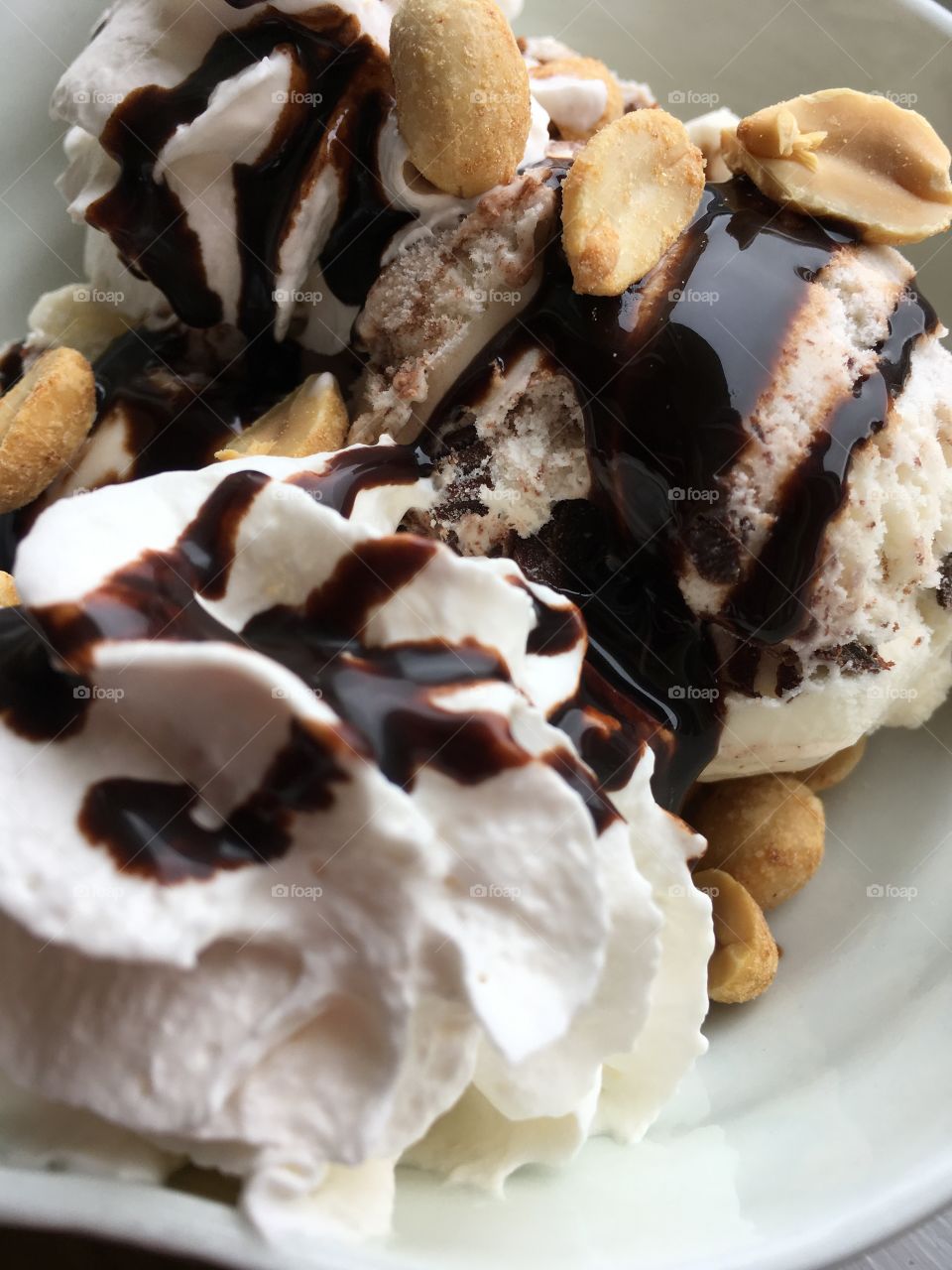 Chocolate ice cream sundae with whip cream and peanuts. 