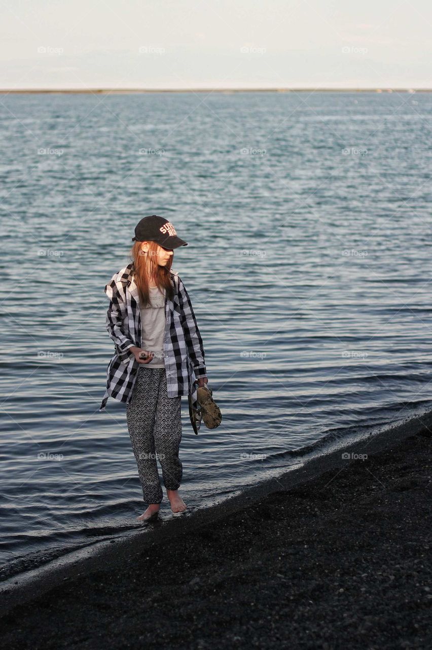 A girl walks along the beach and collects lake