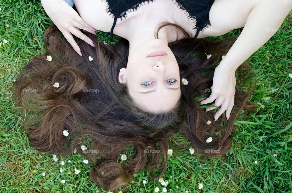 Woman brunette with beautiful natural hair on background of daisies