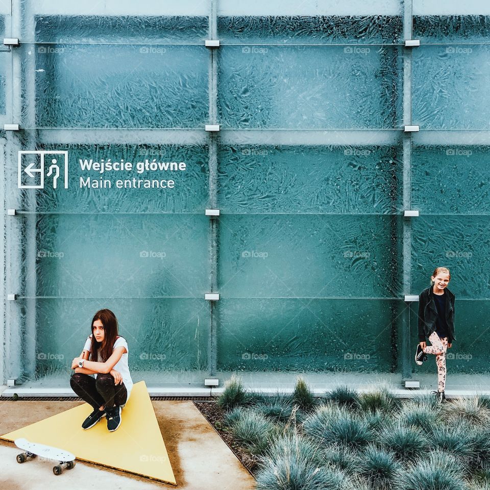 Thoughtful woman with skateboard crouching near entrance