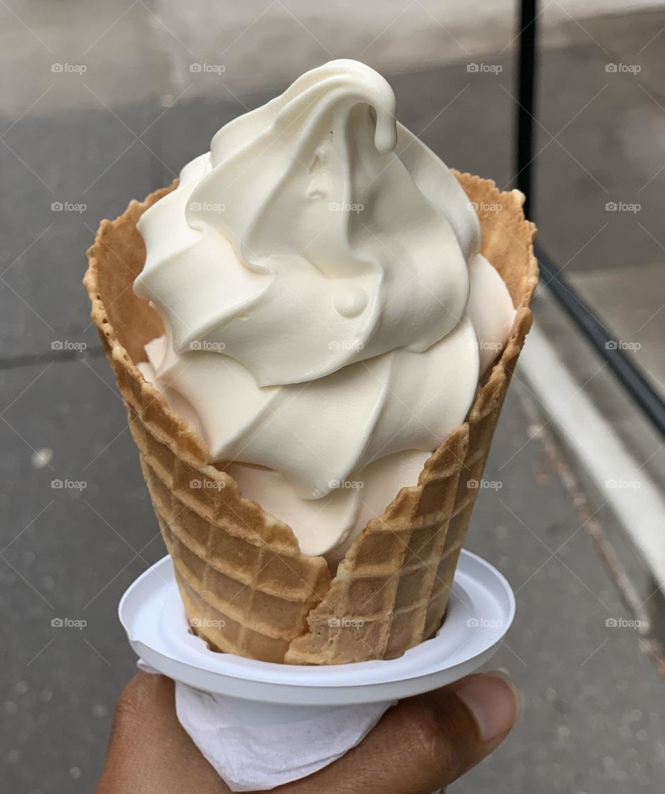 A person holding a vanilla ice cream 