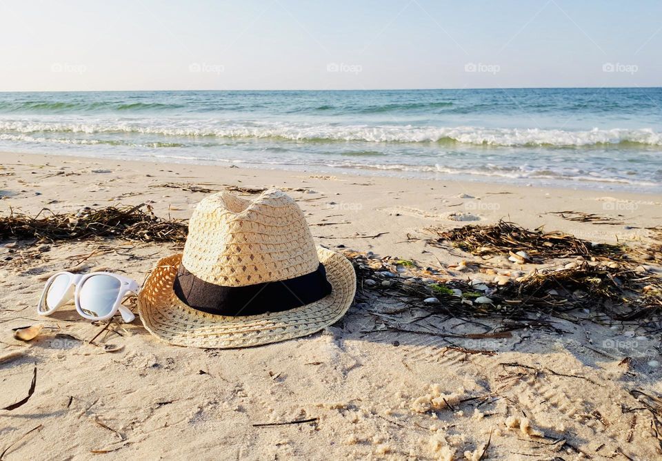 Straw hat and sunglasses on the beach 