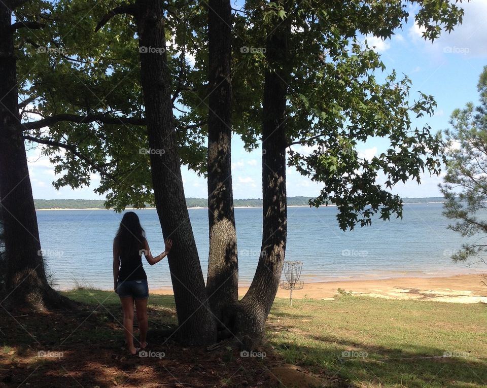 Girl by tree overlooking lake