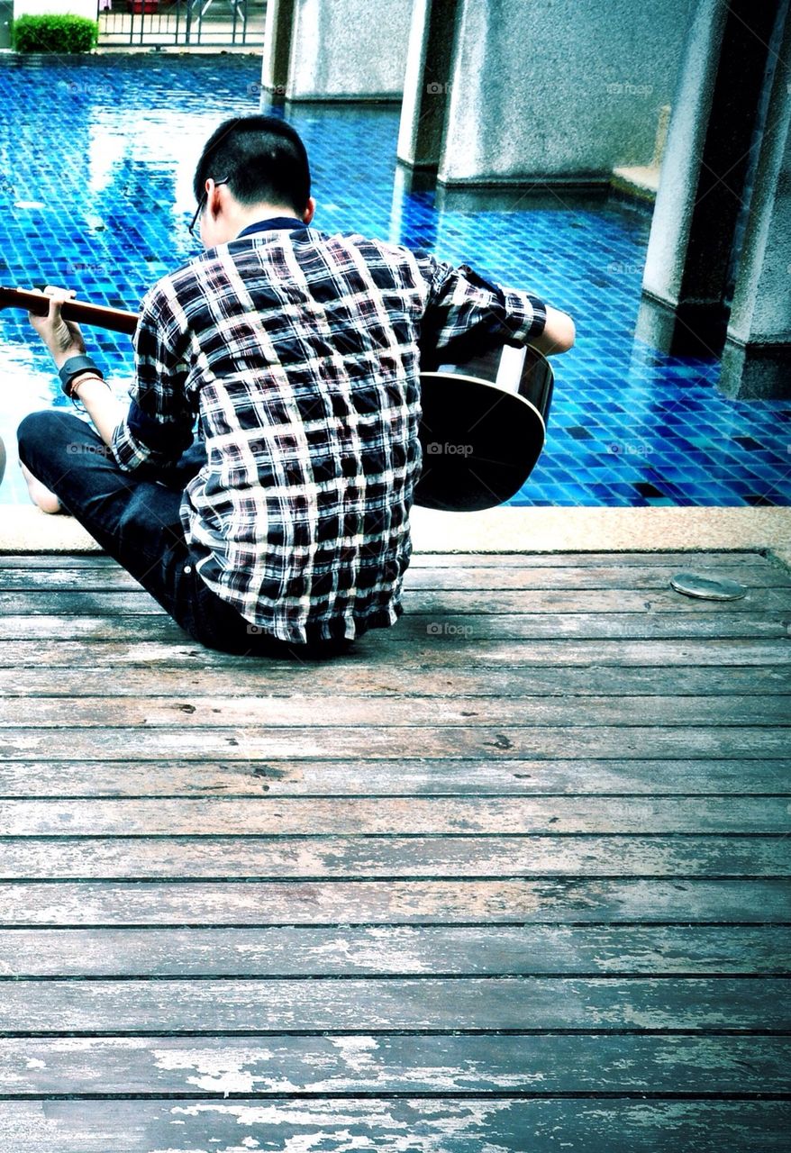 Man play guitar near the pool