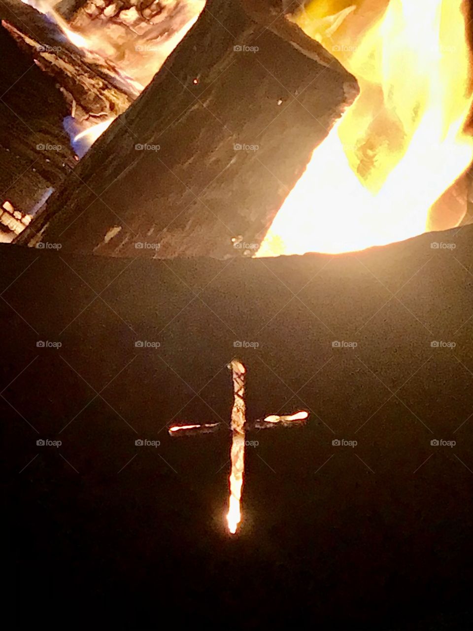 A fire pit with a cross carved into it and a fire glowing around it