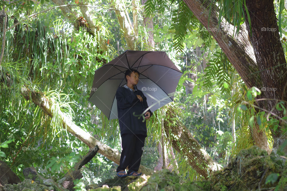 a boy holding an umbrella wearing a black shirt