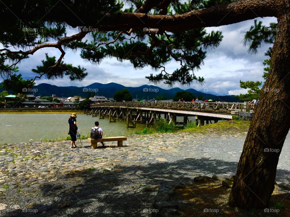 Visitors relax along the riverside near Togetsukyo Bridge, in the Arashiyama area of Kyoto, Japan