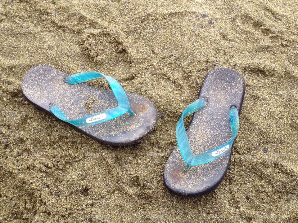 Flip flops on the green sand beach 