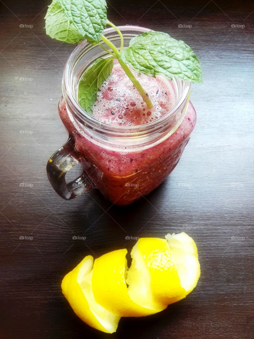 Red fruit smoothie with mint leaves on dark background