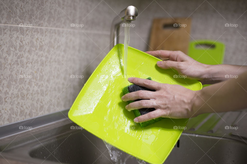 Woman's hands washing green plate