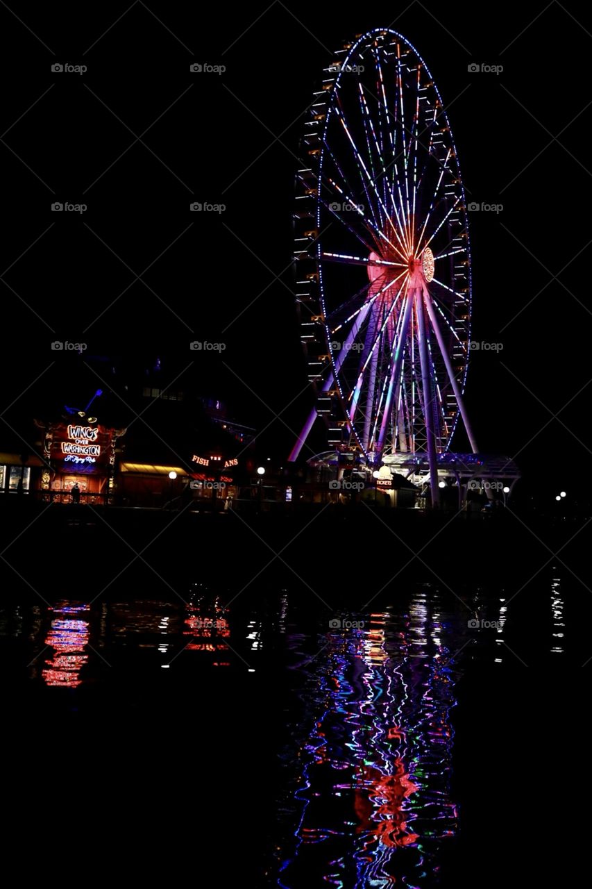 The neon lights of night life at the famous wharf near Pikes Place Market in downtown Seattle Washington, featuring the famous Ferris wheel on the wharf. 