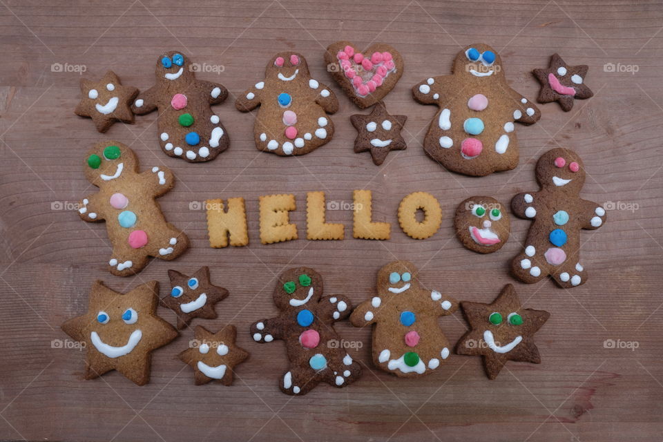 Hello text with biscuit letters and gingerbread cookies on a wooden board