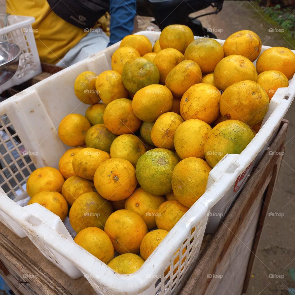 Pile of oranges in a plastic basket ready to be sold