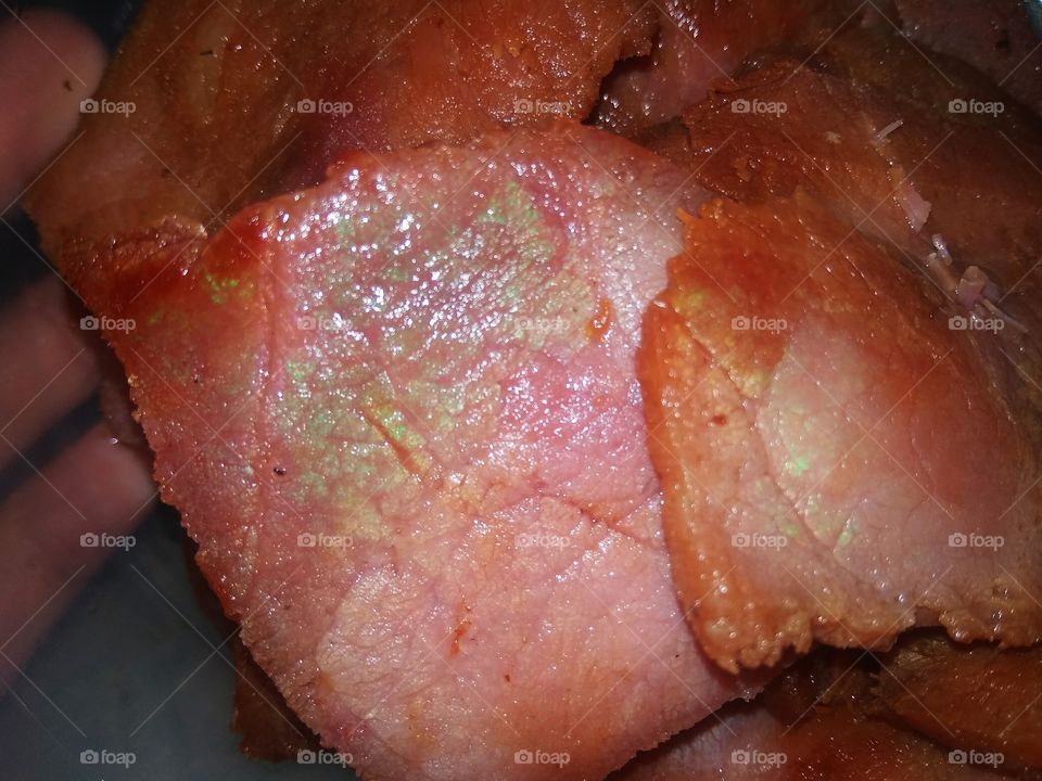 Shiny green chemical reaction on ham or meat.It isn't spoiled. It's just a chemical reaction from slicing using metal knife.