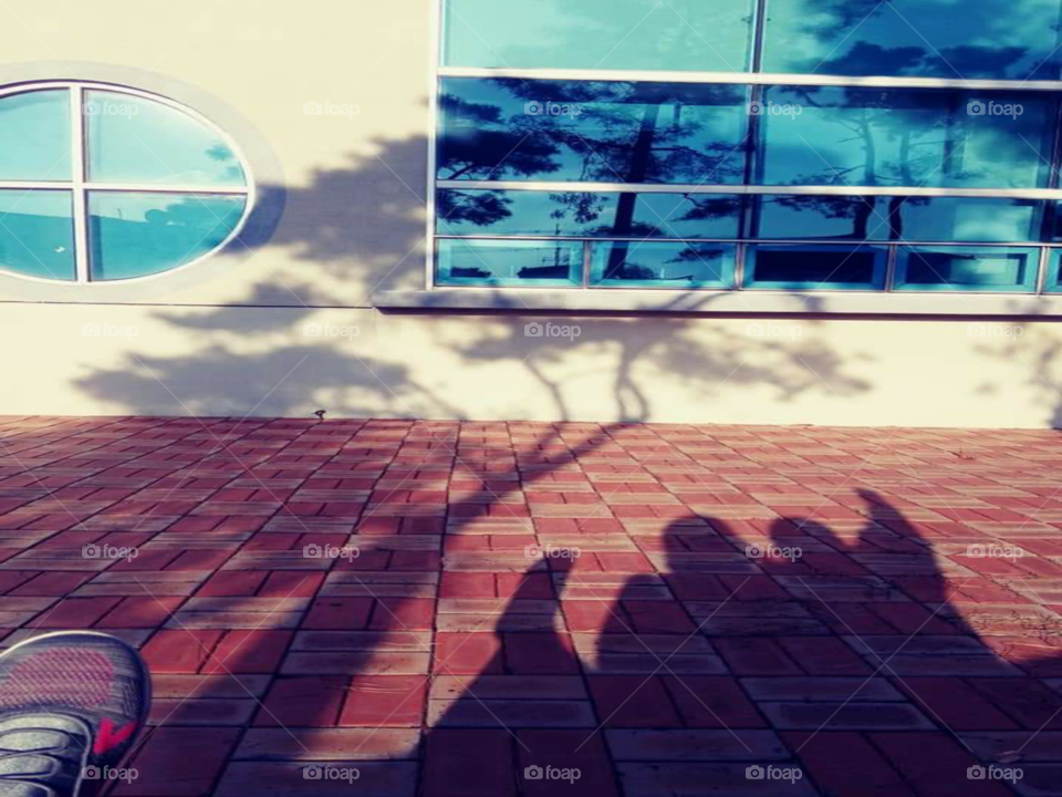 a shadow of a mother and child hugging each other while the mother raising up her legs up high and the child raising her right arms up high to make some fun. they are laughing each other.