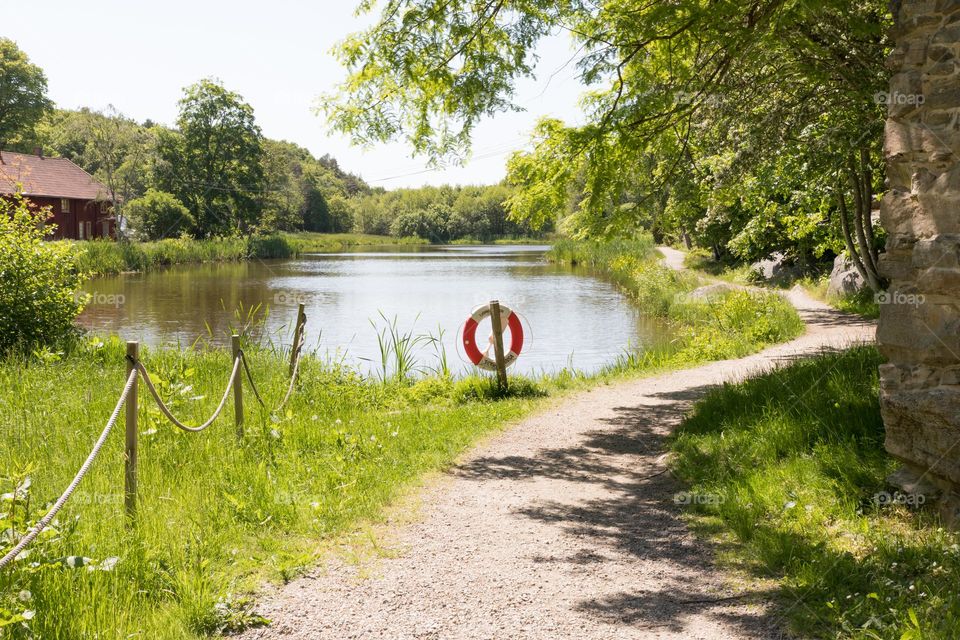 Hiking trail by a small lake and forest at Sundsby in the Swedish countryside on a beautiful sunny summer day 
