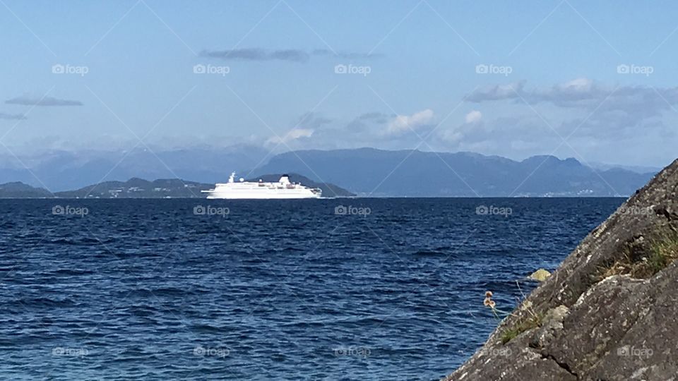 Cruise ship passing in the fjord. Calm sea, no waves. Almost no clouds, and the sun is shining. Taken in Norway.