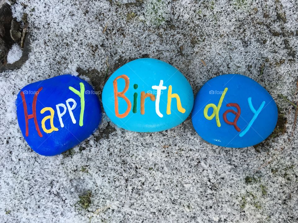 Rocks message of Happy Birthday with snow background 