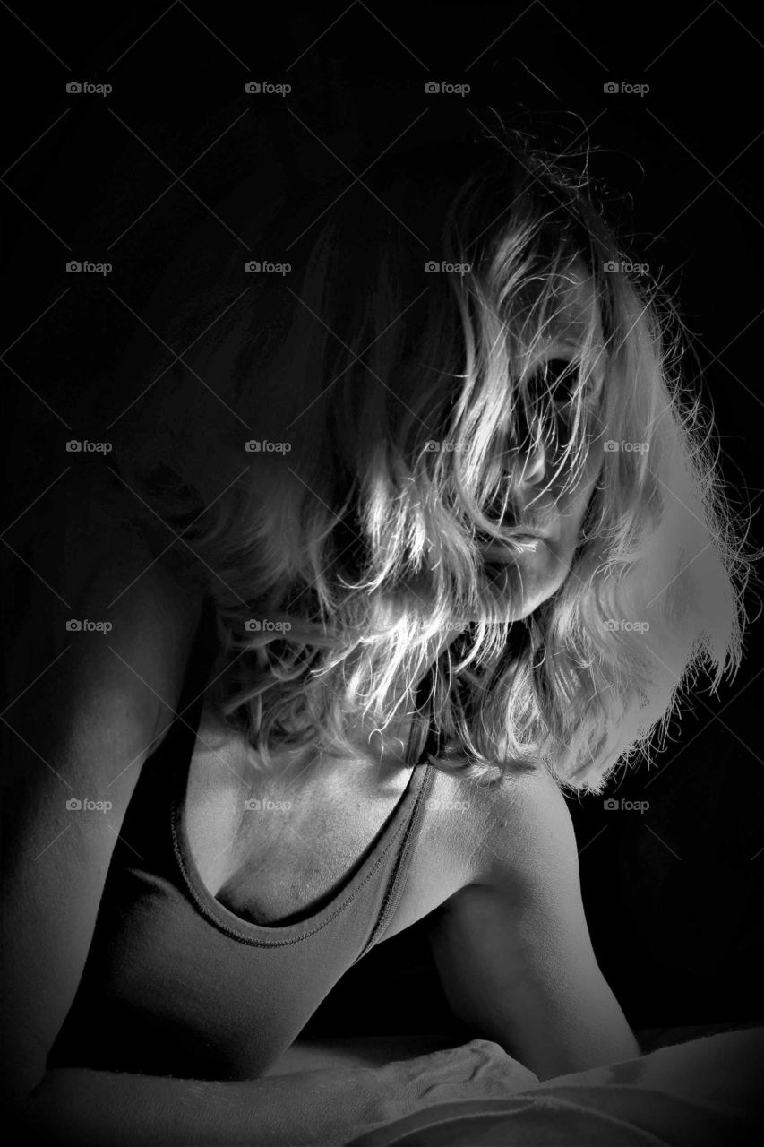 woman with wild curly blond hair close up low key black and white portrait