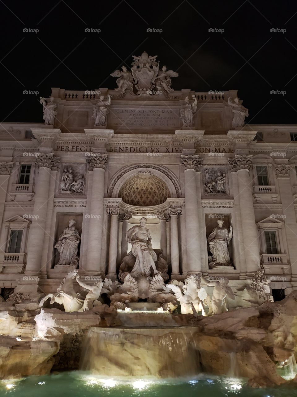 The famous Trevi fountain in Rome, Italy, Europe, in evening time with lights illuminating the statues and water.