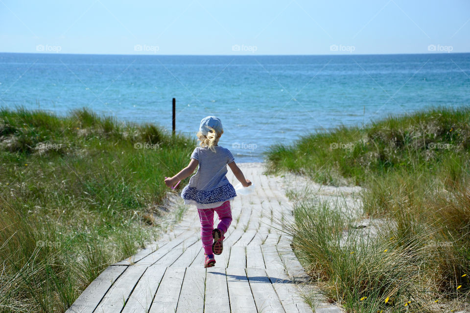 Little girl running down to the beach to play.