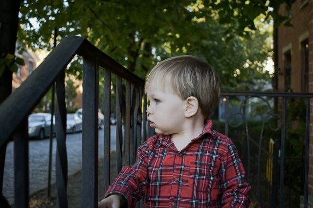 Cute curious toddler watching street from porch 
