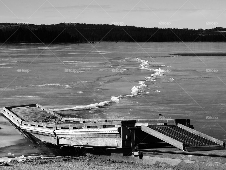 A small wooden boat dock lays on top of the frozen over Thompson Reservoir in Southern Oregon on a cold winter day. 