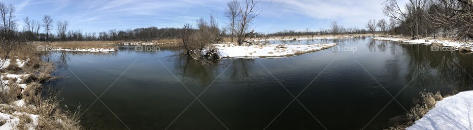 Panoramic Winter Riverscape - Beautiful Cold Flowing Water and Snow Covered Grass - Winter in Wisconsin - Blue Sky and Sunshine with Bare Trees