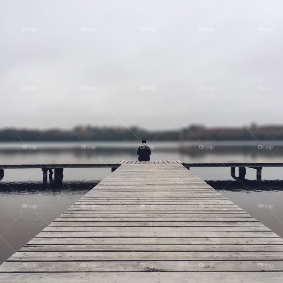 Person sitting on pier at lake