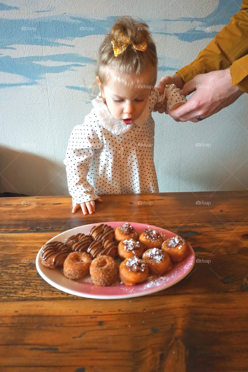 Little cute girl looking at sweet cookies