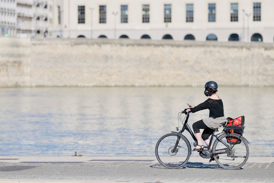 Milenilal girl rides a bicycle along the city promenade in a special protective mask and helmet