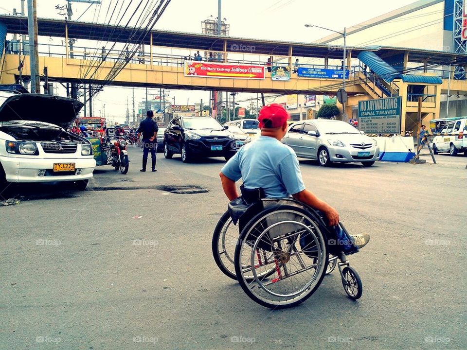 Disabled man in a wheelchair waits at an intersection for his turn to