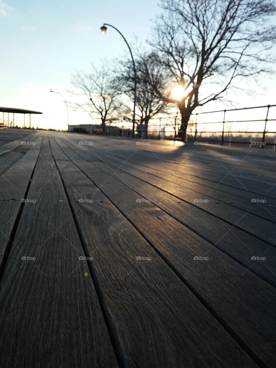 Winter sun descending behind barren trees along the boardwalk of Ocean Beach, Connecticut [original photo].